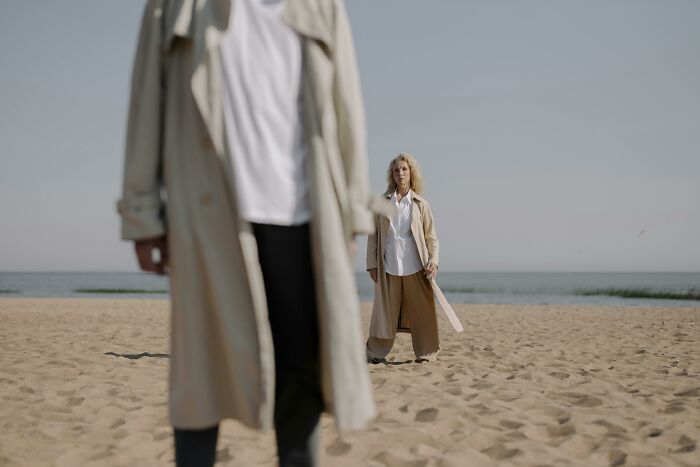 People in trench coats standing on a beach, evoking a mysterious and eerie atmosphere.