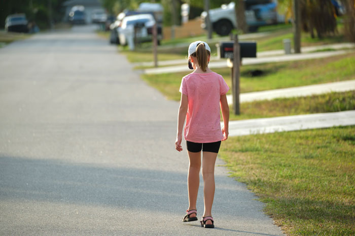 Teen girl in pink shirt walking down a suburban street, summer afternoon. Teen girl in pink shirt walking down a suburban street, summer afternoon.