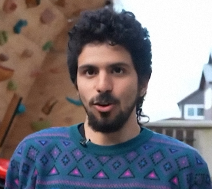 Man shares his incredible survival story, wearing a patterned sweater, standing outdoors.