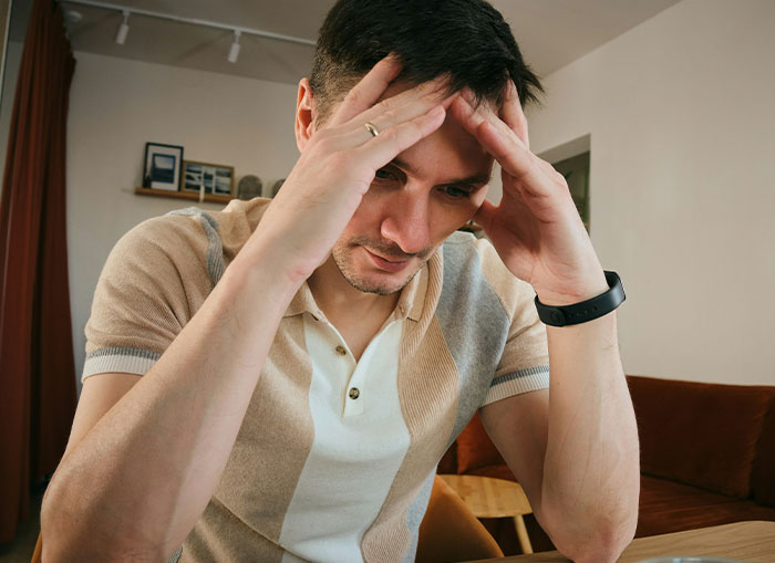 Man showing stress, resting head in hands, related to vasectomy discussion.