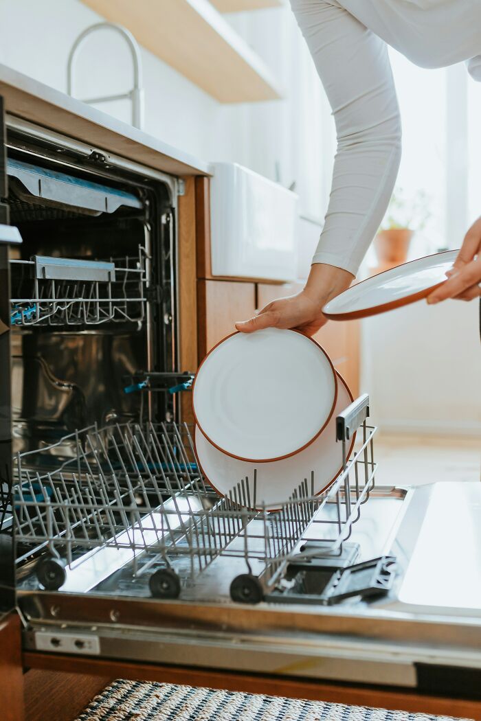 Person loading plates into a dishwasher, illustrating a worst Valentine’s Day gift scenario.