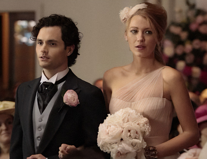 Blake Lively in a pink dress holding flowers next to Penn Badgley n a tuxedo at a formal event in a scene from "Gossip Girl.