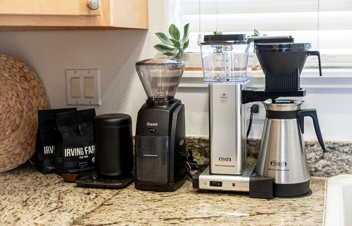 Coffee maker and grinder on granite countertop.