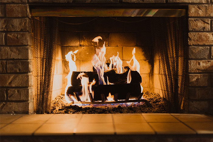 Fireplace with burning logs, casting a warm glow, evoking haunting stories found online.