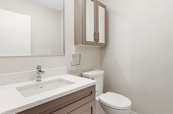 Modern bathroom with beige cabinets, a white countertop, and a wall mirror; minimalist design.