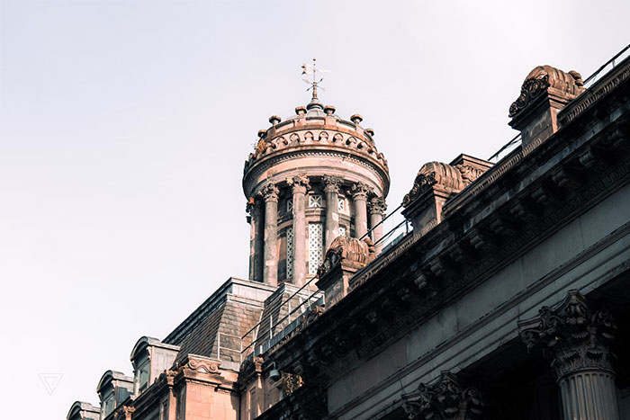 Historic architectural details of a grand building's tower, highlighting ornate stonework against a clear sky.