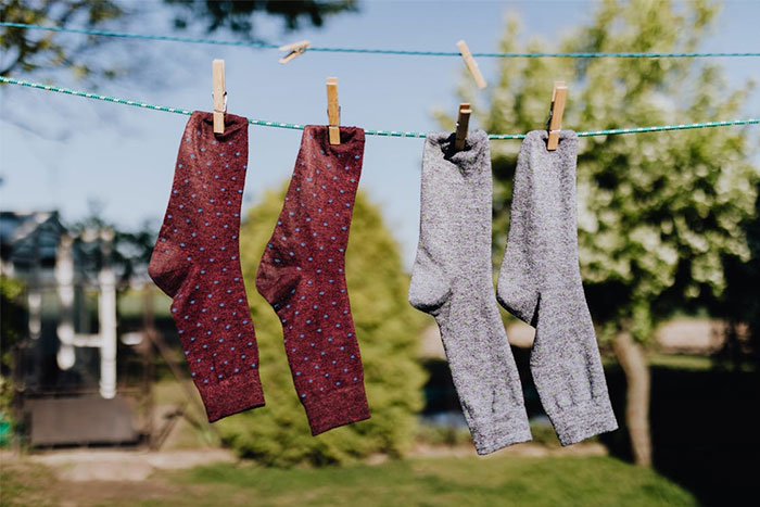 Darkest stories: mismatched socks hanging on a clothesline in a sunny garden setting.