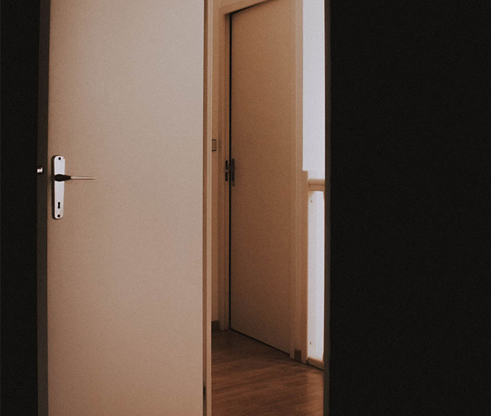 Open door in dimly lit hallway, evoking a sense of haunting and mystery.