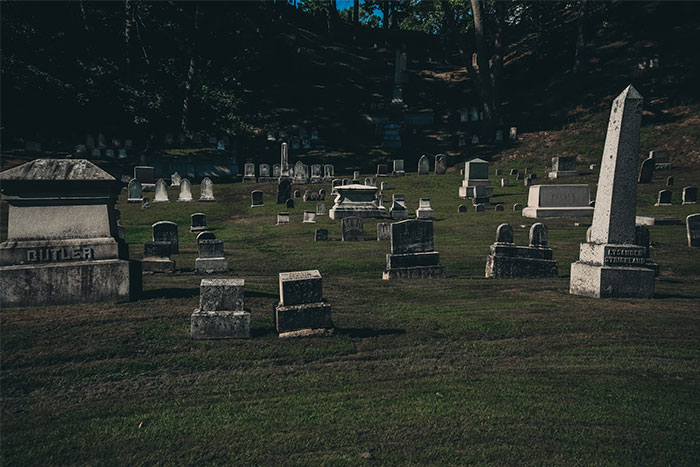 Graveyard with various tombstones casting shadows, evoking haunting and dark stories.