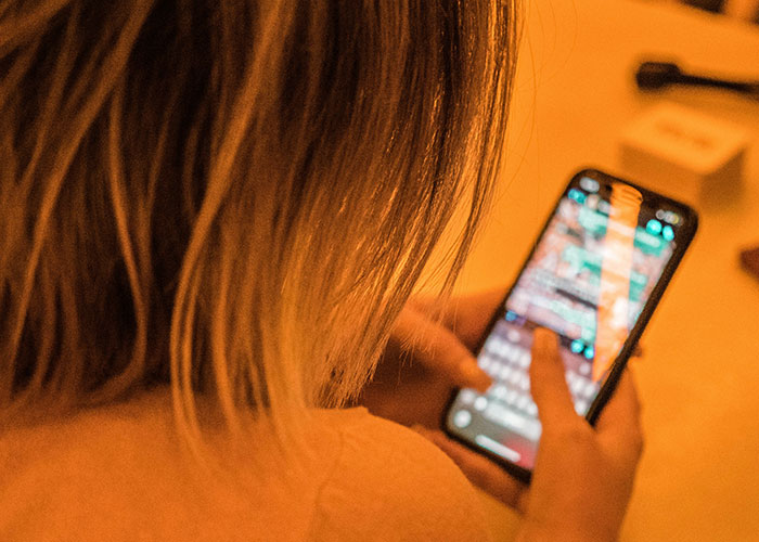 Woman using smartphone, focused on screen, typing a message.