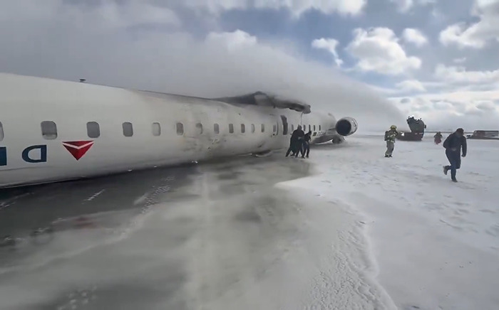 Delta Airlines plane upside down after crash landing on icy terrain, surrounded by rescue personnel. Delta Airlines plane upside down after crash landing on icy terrain, surrounded by rescue personnel.