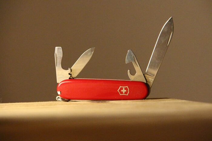 Red Swiss Army knife with multiple blades open, showcasing durable design for longevity.