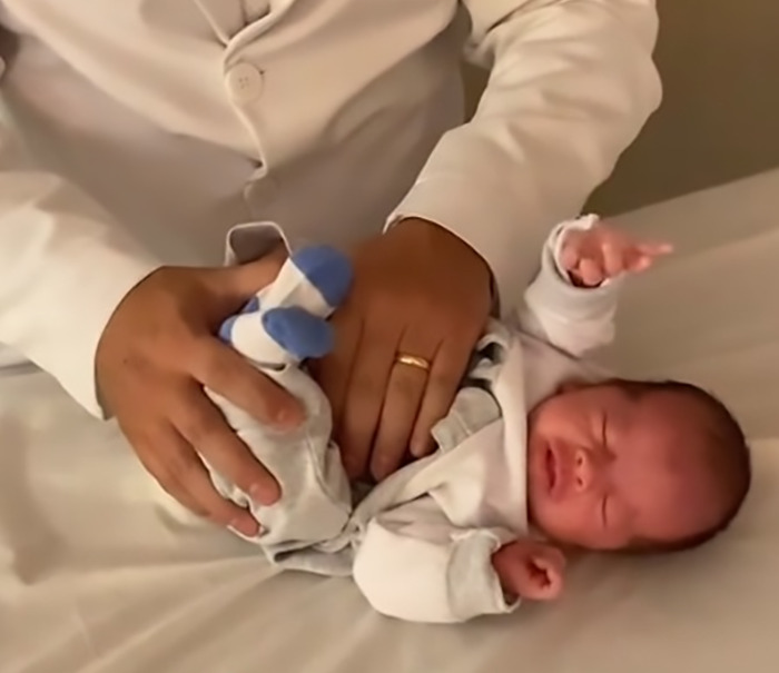 Doctor demonstrating baby farting tips on a newborn, evoking humorous reactions. Doctor demonstrating baby farting tips on a newborn, evoking humorous reactions.