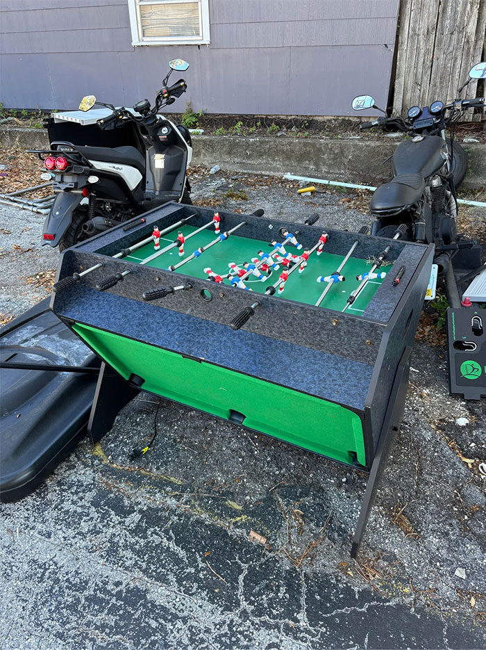 Foosball table found while dumpster diving near two parked scooters.