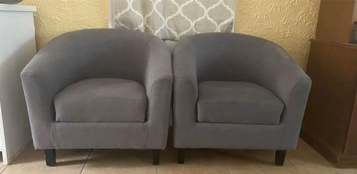 Two gray armchairs found while dumpster diving, placed side by side in a room.