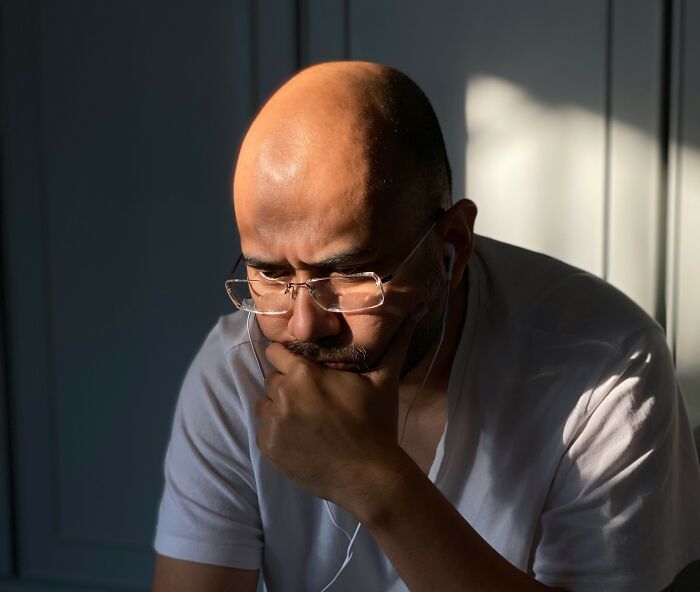 Man deep in thought with glasses and earphones, reflecting on memorable words from his father.