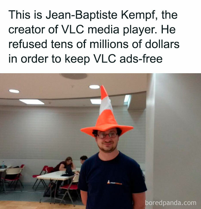 Man with traffic cone hat in a room, wearing glasses and a blue VLC shirt, emphasizing simple interesting facts.