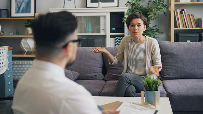 Woman discussing untrainable dog issues with man in living room setting.