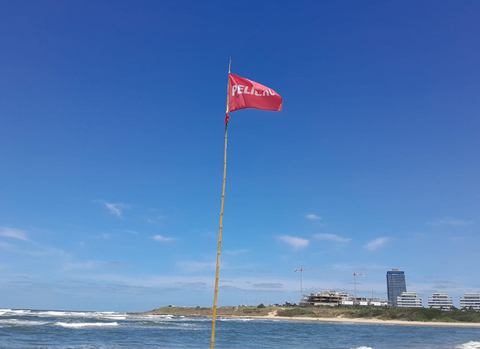 Red warning flag on a beach, indicating caution for lifeguards and swimmers in a coastal setting.