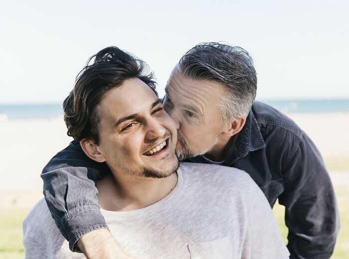 Father and son share a joyful moment outdoors, with the father embracing his smiling son warmly.
