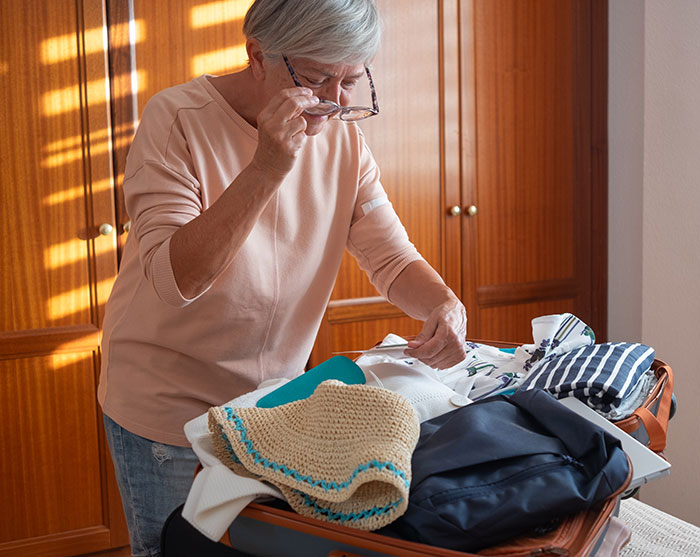 Elderly woman sorting clothes in an apartment, symbolizing MIL issues driving residents away. Elderly woman sorting clothes in an apartment, symbolizing MIL issues driving residents away.