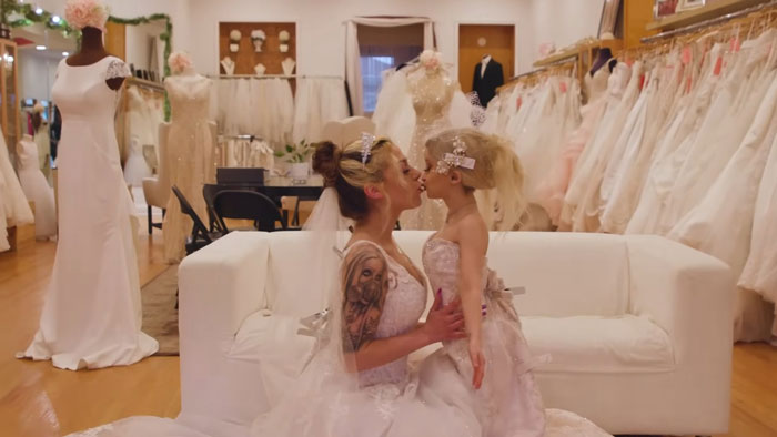 Woman and fianc&eacute;e wearing bridal dresses in a boutique, sparking backlash over "peculiar" appearance.