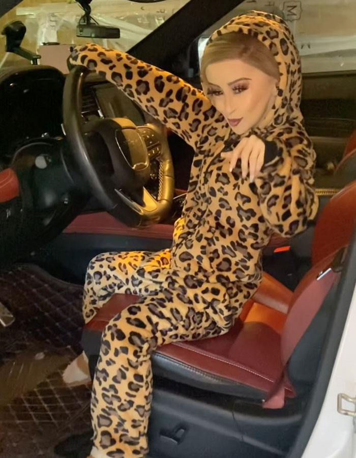 Woman in leopard print outfit sitting in a car, facing backlash for a peculiar appearance.