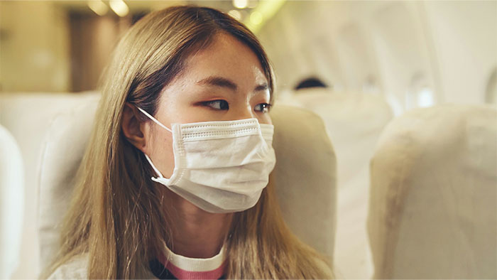 Passenger wearing a mask on an airplane, highlighting flying etiquette rules.