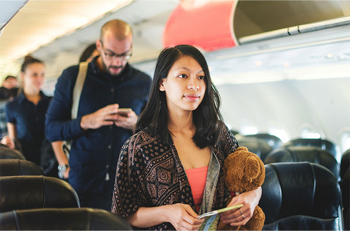 Passengers on a plane, some holding belongings, reflecting common flying etiquette scenarios.