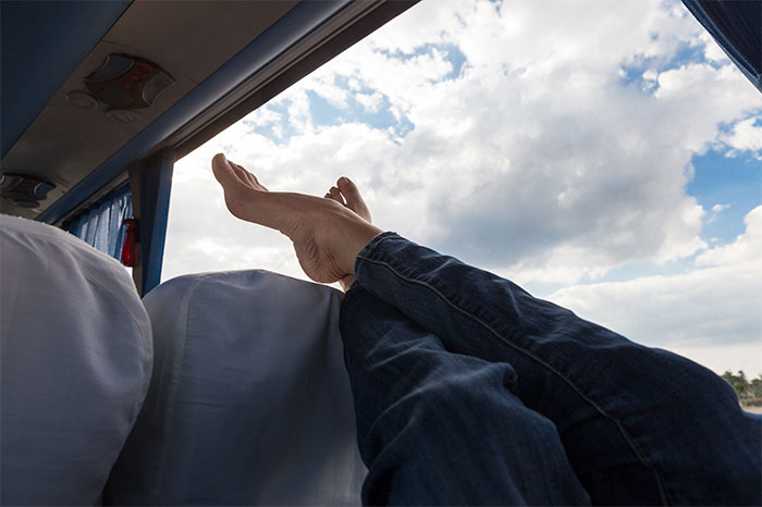Passenger with legs stretched out against airplane window, ignoring flying etiquette.