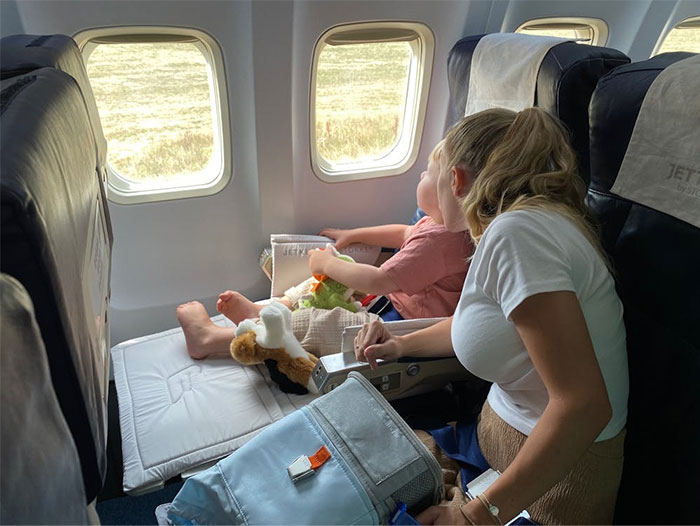Woman and child on plane with a footrest, illustrating flying etiquette.