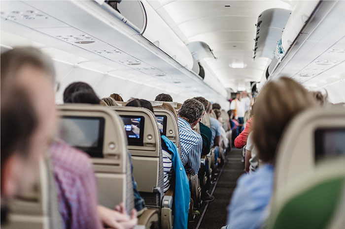 Passengers seated in an airplane aisle, demonstrating common flying etiquette practices.