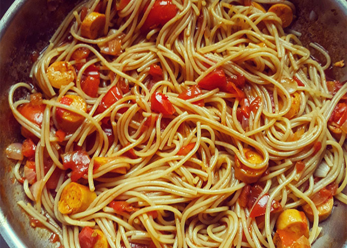 Spaghetti with tomatoes and vegetables in a pan, featuring a food people started loving when they grew up.