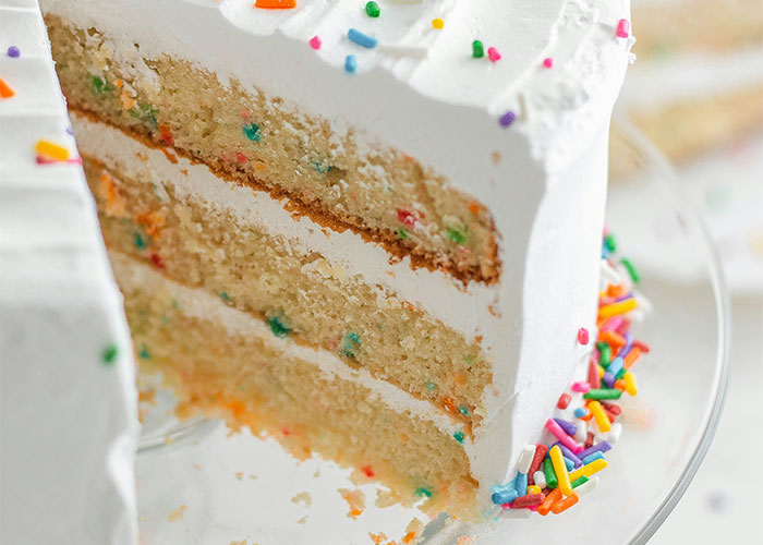 Slice of cake with white frosting and colorful sprinkles, featuring foods that people grow to love as they mature.