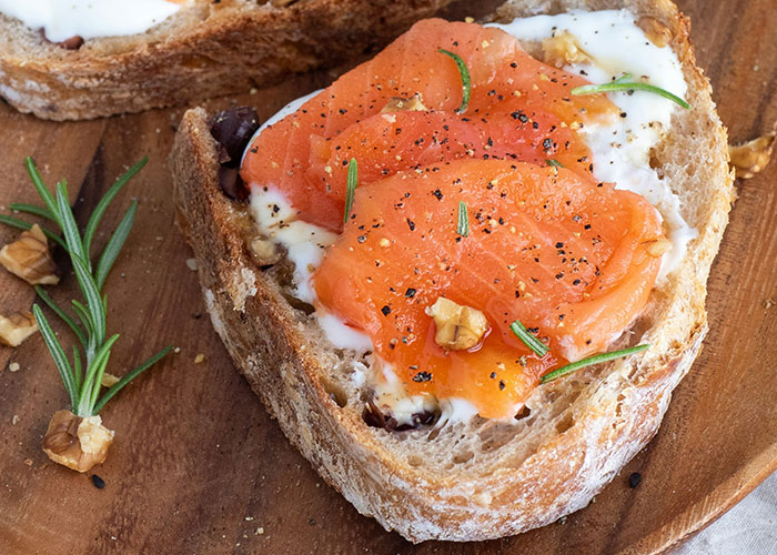 Toasted bread with smoked salmon, garnished with rosemary and walnuts. Foods that people started loving when they grew up.
