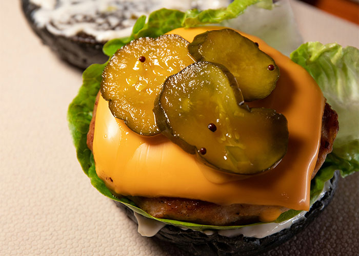 Cheeseburger with lettuce and pickles on a bun, representing foods that people started loving when they grew up.