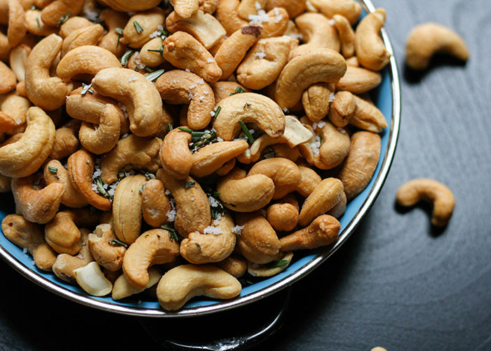 Bowl of roasted cashews with herbs and salt, highlighting foods people love as they grow up.