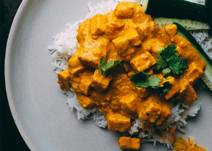 Paneer curry with cilantro over white rice on a plate.