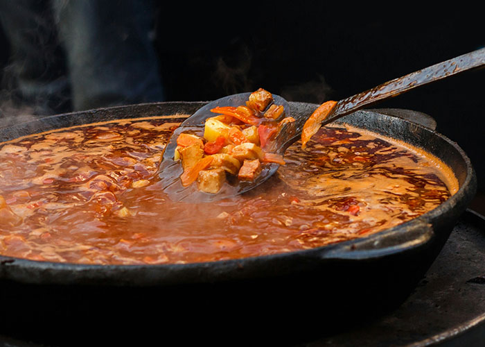 Rich stew simmering in a black pan, highlighting foods that people started loving as they grew up.
