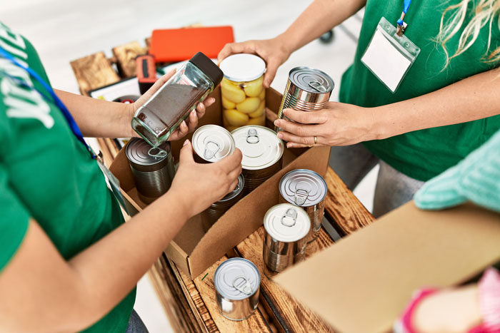 Two people packing canned food and glass jars at a food bank. Two people packing canned food and glass jars at a food bank.