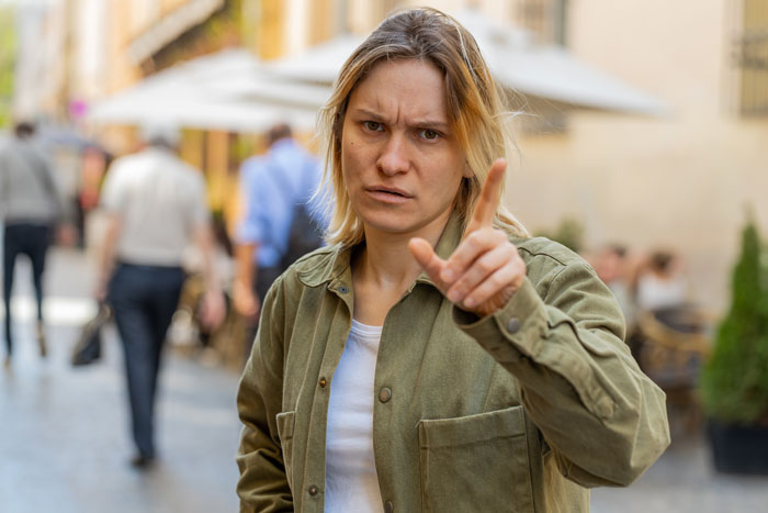Person looking baffled, pointing in concern outdoors, reacting to friends' income deception involving a food bank. Person looking baffled, pointing in concern outdoors, reacting to friends' income deception involving a food bank.