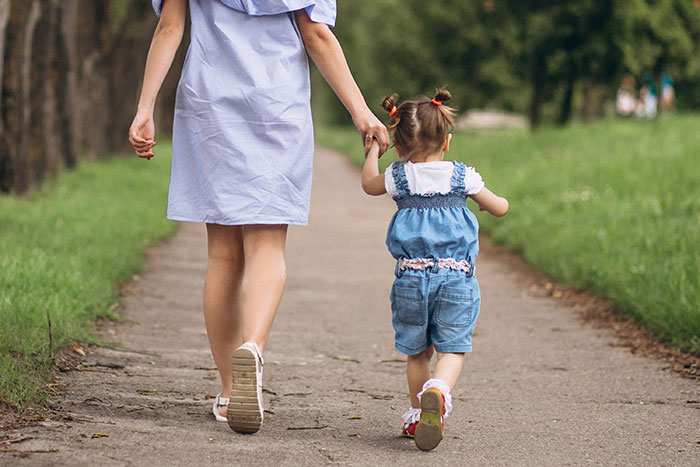 Woman holding child's hand on a path, emphasizing a child-free theme.