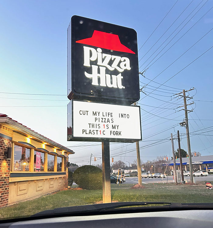 Funny sign on Pizza Hut billboard with playful text about pizza and plastic fork.