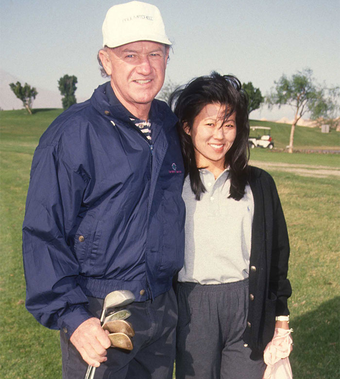 Man and woman on a golf course with clubs, main SEO keyword: Gene Hackman&rsquo;s wife.