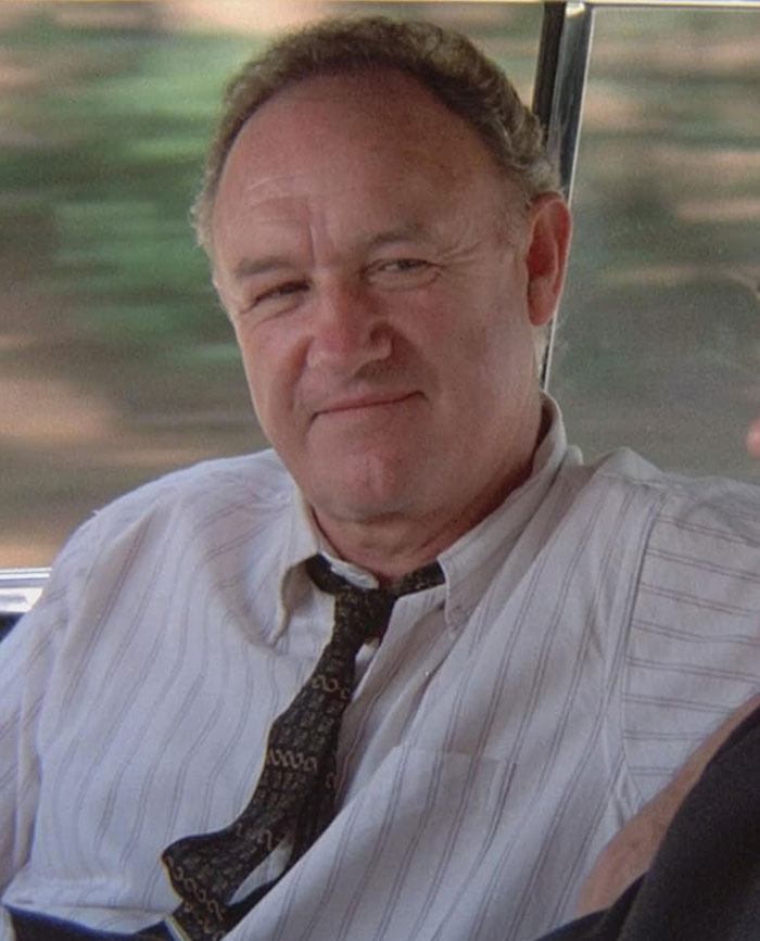 An older man in a white shirt and tie, sitting and smiling, representing celebrities.