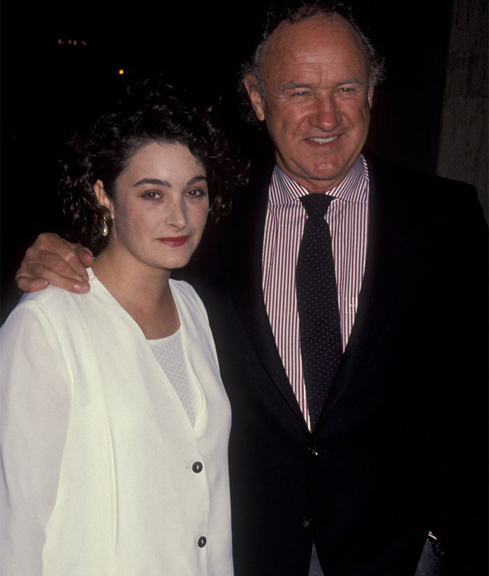 Man in a suit with a woman in a white outfit at an evening event.