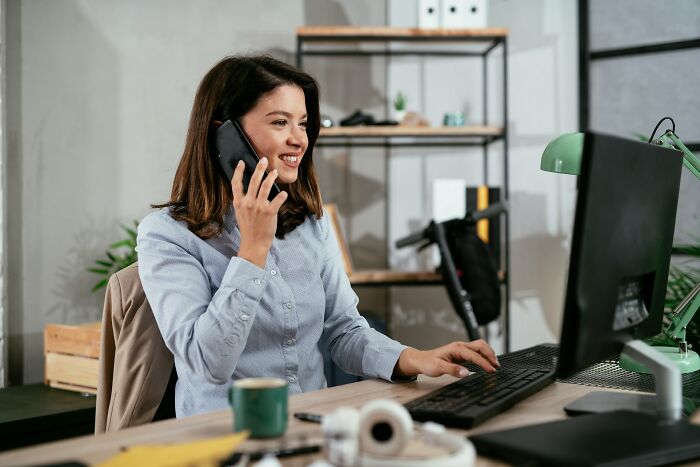 Woman working at a desk, smiling while on the phone, challenging job assumptions.