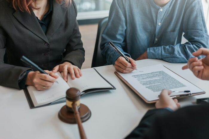 Professionals in a meeting, writing notes, with a gavel on the table, discussing potential job changes.