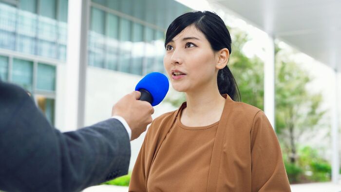 Person being interviewed with blue microphone, discussing industry employment changes.