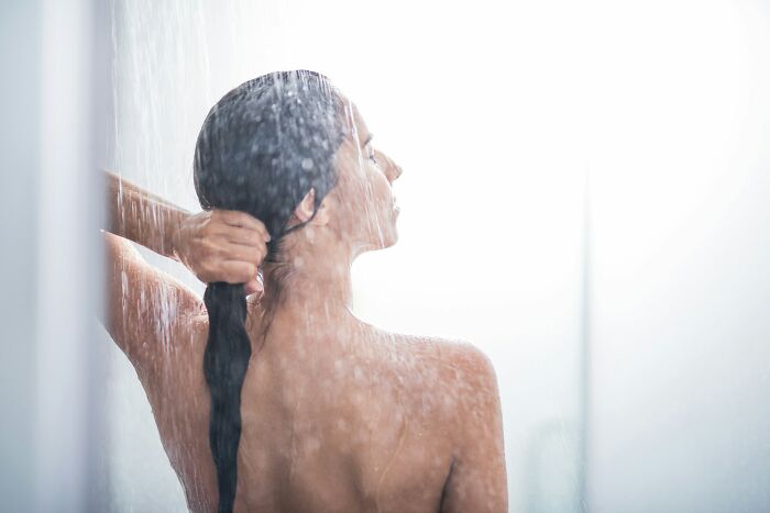 Person showering, illustrating a moment of frugal self-care and relaxation.